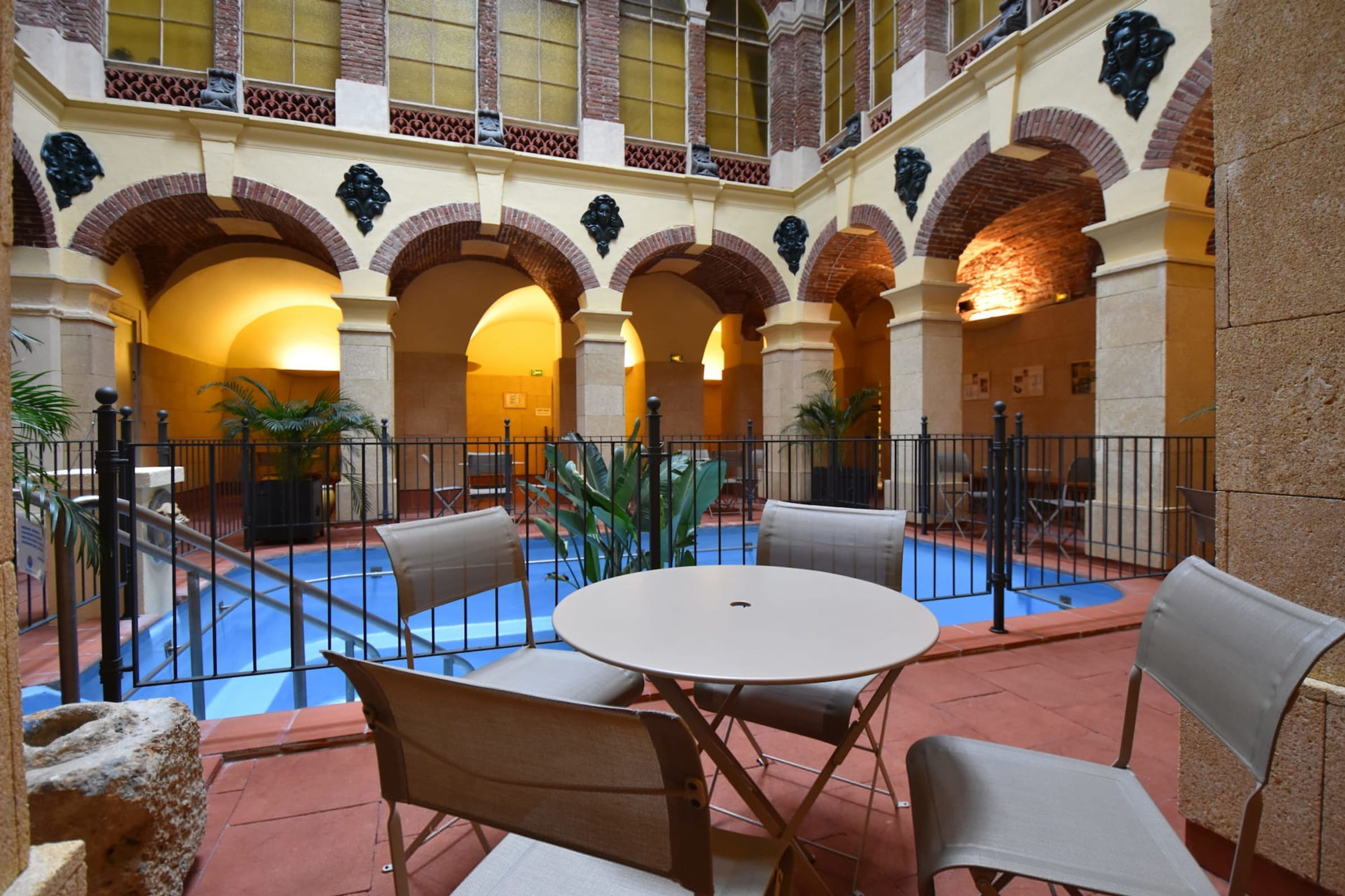 A courtyard with a pool, outdoor seating, and a high ceiling with arches.
