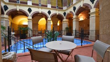 A courtyard with a pool, outdoor seating, and a high ceiling with arches.