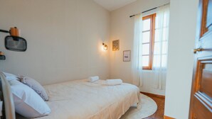 A bedroom with a bed, a round rug, a wall-mounted light fixture, and a window with curtains. - Casa Vama Pool Private Cinema (Amelie-les-Bains-Palalda)
