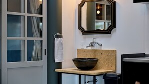 Ein Badezimmer mit großem Fenster, einem Waschbecken mit Aufsatzbecken, einem Spiegel und einem Handtuchhalter.