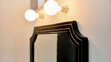 A mirror with a black frame and two round lights above it.