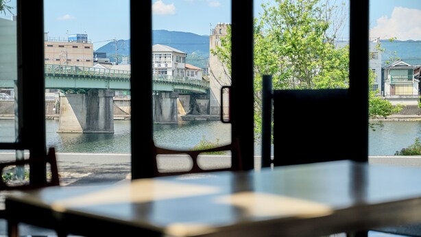Ein Tisch und Stühle in einem Raum mit Blick auf eine Brücke über dem Wasser.