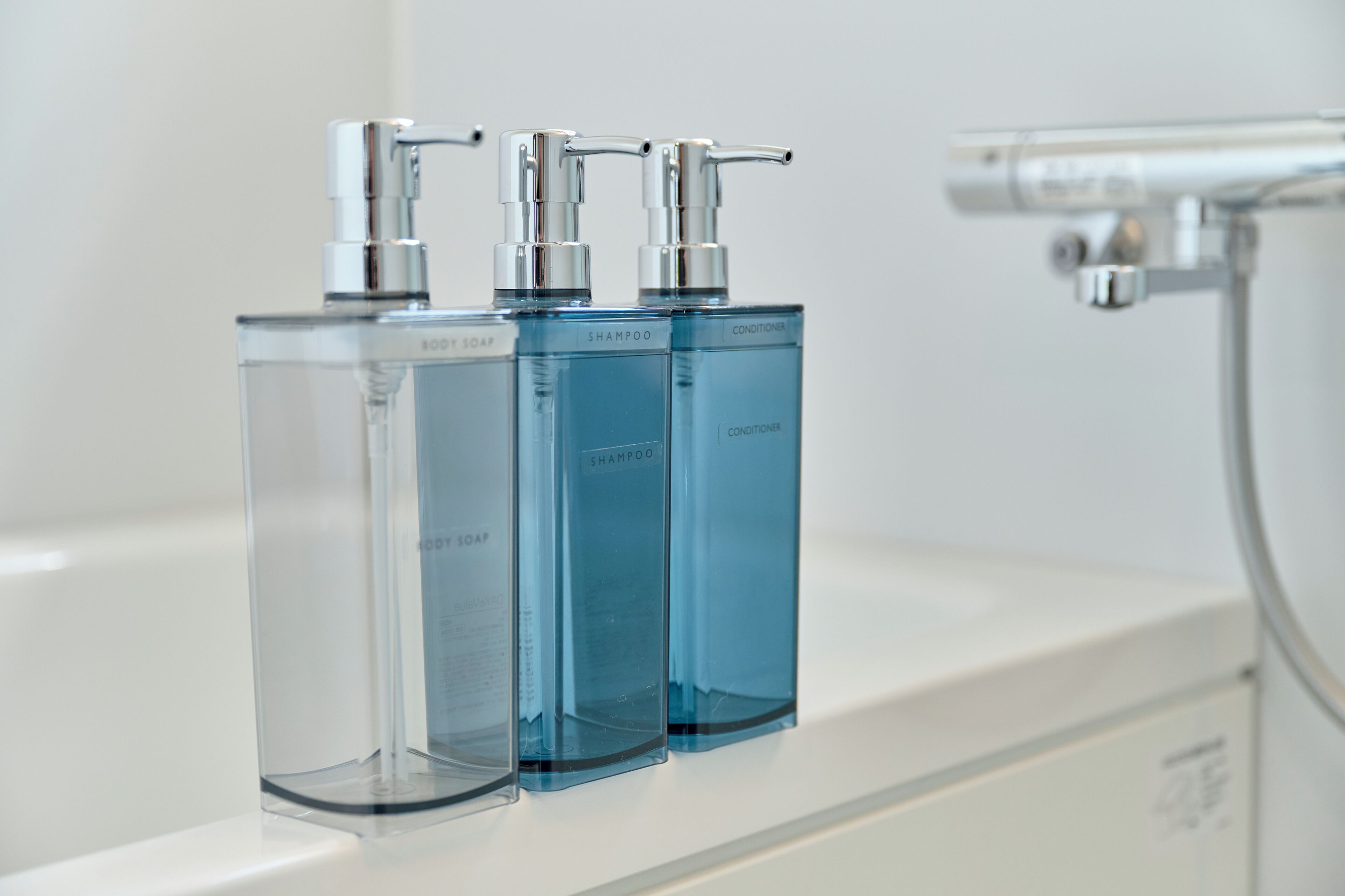 Three clear bottles of liquid on a white surface, likely a bathroom counter.