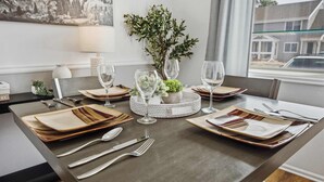 A dining table set with plates, cutlery, and glasses, surrounded by a decorative centerpiece and a view of the outside. - Townie at the Foothills | Hop, Skip & Hike (Fort Collins)