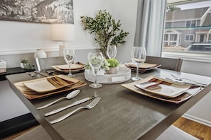 A dining table set with plates, cutlery, and glasses, surrounded by a decorative centerpiece and a view of the outside. - Townie at the Foothills | Hop, Skip & Hike (Fort Collins)