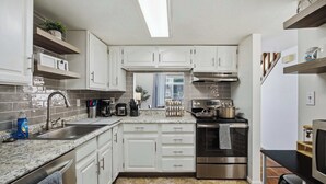 A compact kitchen with white cabinetry, a stainless steel oven, and a built-in microwave. - Townie at the Foothills | Hop, Skip & Hike (Fort Collins)