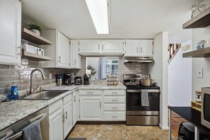 A compact kitchen with white cabinetry, a stainless steel oven, and a built-in microwave. - Townie at the Foothills | Hop, Skip & Hike (Fort Collins)