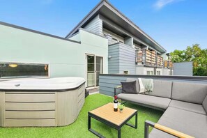 A modern outdoor living area with a hot tub, a sofa, and a small table. - Rocky Retreat Near Old Town | Hot Tub | Fireplace (Fort Collins)