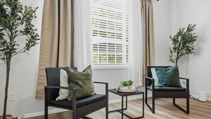 Una habitación con dos sillas, una mesita y una planta en maceta.