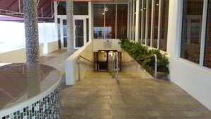 A corridor with a tiled floor, a glass door, and a staircase leading to an upper level. - Beautiful Oceanfront Studio in Marco Polo Sunny Isles Beach (Sunny Isles Beach)