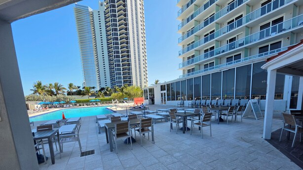 A poolside area with outdoor seating and a view of tall buildings. - Beautiful Oceanfront Studio in Marco Polo Sunny Isles Beach (Sunny Isles Beach)