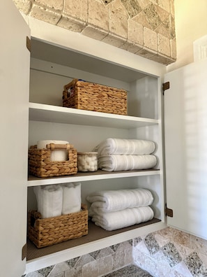 A white shelf with woven baskets, rolled towels, and folded towels. - Cozy & Charming Stay Min from Hobby, NRG, Downtown, NASA (Houston)