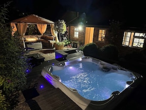 Boblebad med LED-lys, træterrasse og overdækket opholdsområde med hynder.