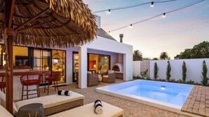 Un espacio exterior moderno con piscina, asientos y barra.