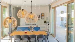 A modern dining area with a wooden table, grey chairs, and pendant lights. - Beautiful home in Zmijavci with sauna (Zmijavci)