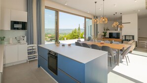 A modern kitchen with a large island, dining area, and a view of the countryside. - Beautiful home in Zmijavci with sauna (Zmijavci)