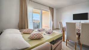 Ein Hotelzimmer mit Bett, Fernseher, Esstisch mit Stühlen und Blick durch eine Schiebetür.