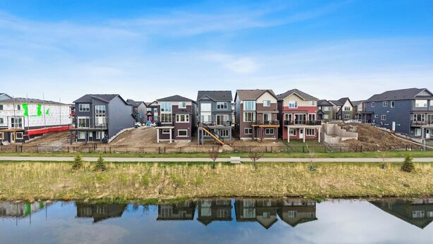 A row of modern residential buildings with a clear reflection in a body of water. - Mallard Cove | Pond Views | Pets Ok | Playground (Calgary)