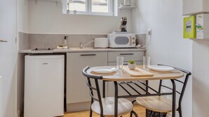 Ett kompakt kök med kylskåp, mikrovågsugn och kaffebryggare. Det finns ett litet matbord med två stolar.