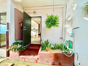 A modern entrance with a black door, potted plants, and a hose on the wall. - Porto Bello, Oceanfront Self Check In (Aguada)