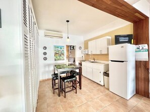 Eine kompakte Küche mit Esstisch, Stühlen, einem Kühlschrank und einer Mikrowelle.