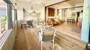 Ein geräumiger Balkon mit Deckenventilator, einem Glastisch mit Stühlen und einer Couch im angrenzenden Wohnbereich.
