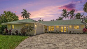 A two-story house with a paved driveway, a garage, and a well-maintained lawn. - Palaco Paradise - Waterfront Oasis with Large Pool (Cape Coral)