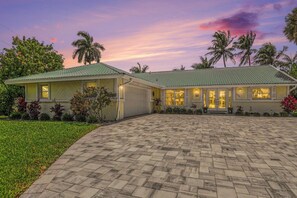 A two-story house with a paved driveway, a garage, and a well-maintained lawn. - Palaco Paradise - Waterfront Oasis with Large Pool (Cape Coral)