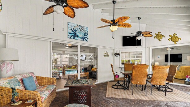 A room with wicker furniture, ceiling fans, and a large window. - Palaco Paradise - Waterfront Oasis with Large Pool (Cape Coral)