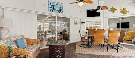 A room with wicker furniture, ceiling fans, and a large window.