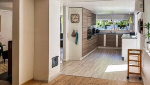 A modern kitchen with wooden cabinets, a built-in oven, and a window overlooking a garden. - Lovely home in Gistrup with WiFi (Gistrup)