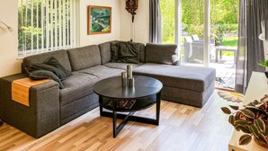 A modern living room with a sectional sofa, a round coffee table, and large windows offering a view of the outdoors. - Lovely home in Gistrup with WiFi (Gistrup)