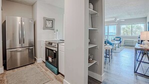 Una cocina moderna con electrodomésticos de acero inoxidable, un comedor con mesa y sillas, y vistas al exterior a través de amplios ventanales.