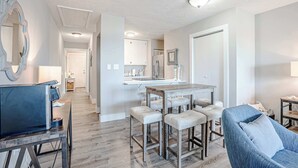 Una cocina moderna con armarios blancos, una isla central con taburetes y una mesa de comedor.