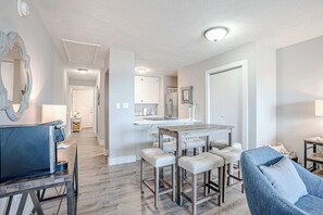 Een moderne keuken met witte kastjes, een centraal eiland met krukken, en een eettafel.