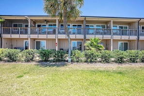 A multi-story hotel with balconies, a palm tree, and a grassy area in front. - Waterfront Condo with Marina Views in Panama City (Panama City)