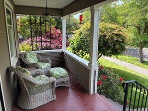 Eine überdachte Veranda mit Korbmöbeln und Blick auf einen Garten.