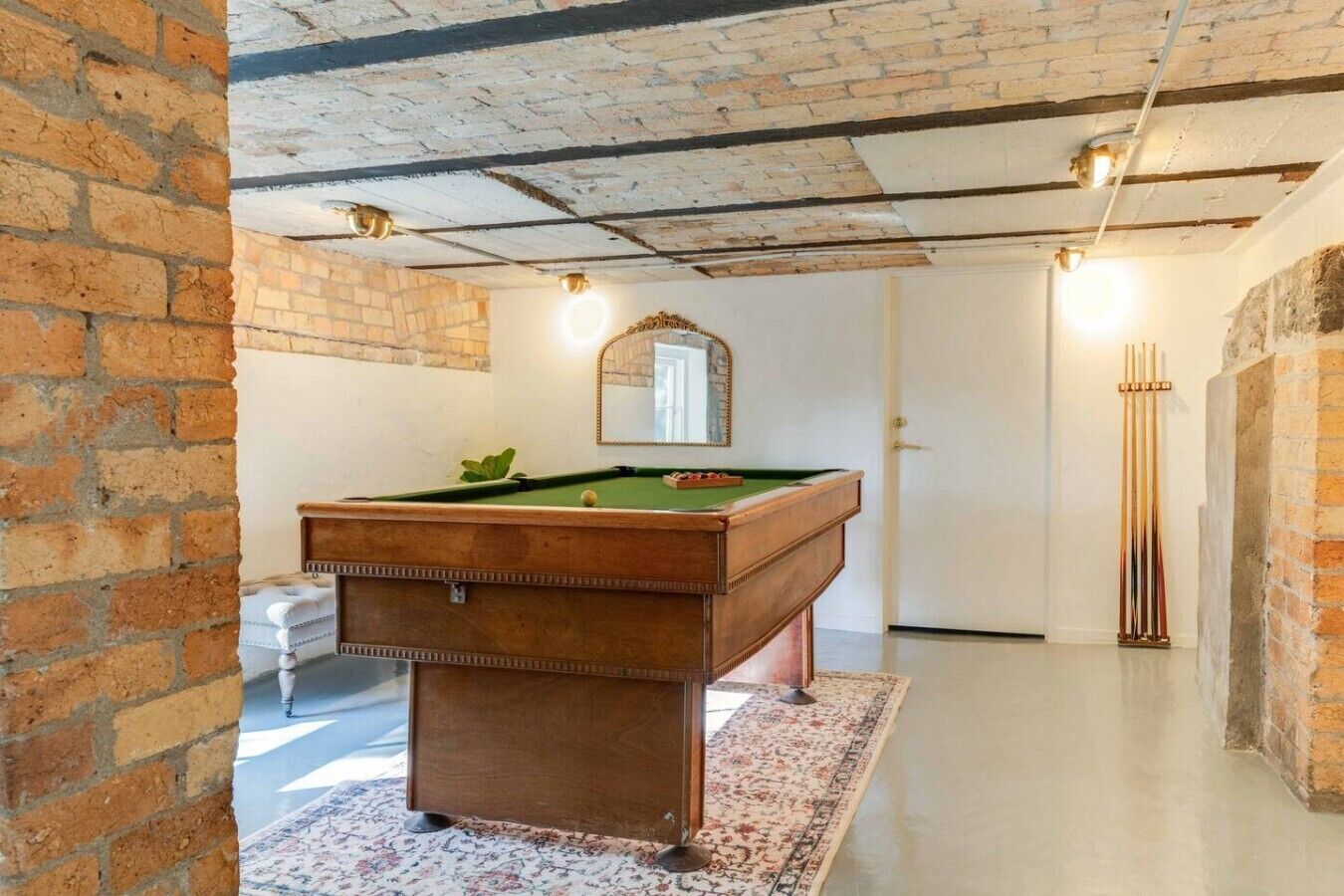 Een biljarttafel in een ruimte met zichtbare bakstenen muren en een houten plafond.