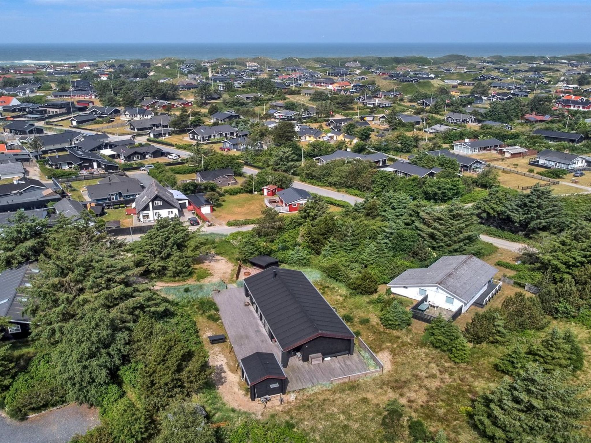 Vue aérienne d’un quartier résidentiel avec des maisons, des routes et de la végétation.