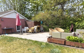 Eine Terrasse mit Gartenmöbeln, einem Geräteschuppen und einem Gartenbereich.
