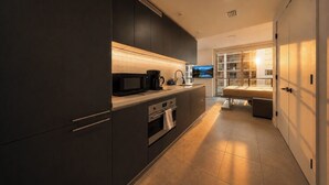 A modern kitchen with dark cabinetry, a built-in microwave, and a coffee maker. - Palm Bay View Suites (Miami)