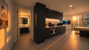 A modern kitchen with dark cabinetry, a built-in oven, and a large window. - Palm Bay View Suites (Miami)