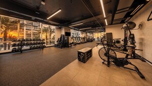 A gym with exercise equipment, large windows, and a view of palm trees. - Palm Bay View Suites (Miami)