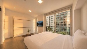 A modern bedroom with a large bed, a TV, and a balcony with a city view. - Palm Bay View Suites (Miami)