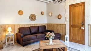 Ein Wohnzimmer mit einem braunen Ledersofa, einem Holztisch mit Blumenvase, einer weißen Lampe und einer Holztür.