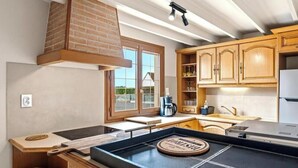 Eine Küche mit Holzausstattung, einem Backsteinofen, einem Fenster und einer Kaffeemaschine.
