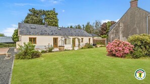 Ein Haus mit geneigtem Dach, einer Veranda und einem gepflegten Rasen.