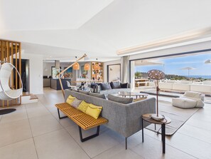 Ein modernes Wohnzimmer mit einer Couch, einem Hängesessel, einem Essbereich und Blick ins Freie.