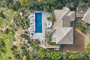 Eine Vogelperspektive auf ein Haus mit Pool, Terrassenmöbeln und einem angelegten Garten.