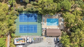 An aerial view of a property with two tennis courts, a swimming pool, and a parking area. - Cozy St. Pete Condo |  Pool | Near Beaches (St. Petersburg)